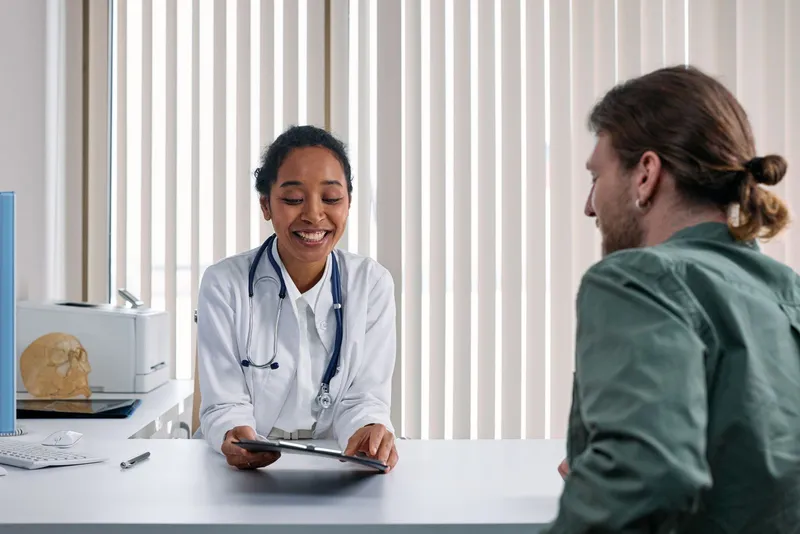 Une médecin montre un dossier sur une tablette à un patient dans une clinique lumineuse