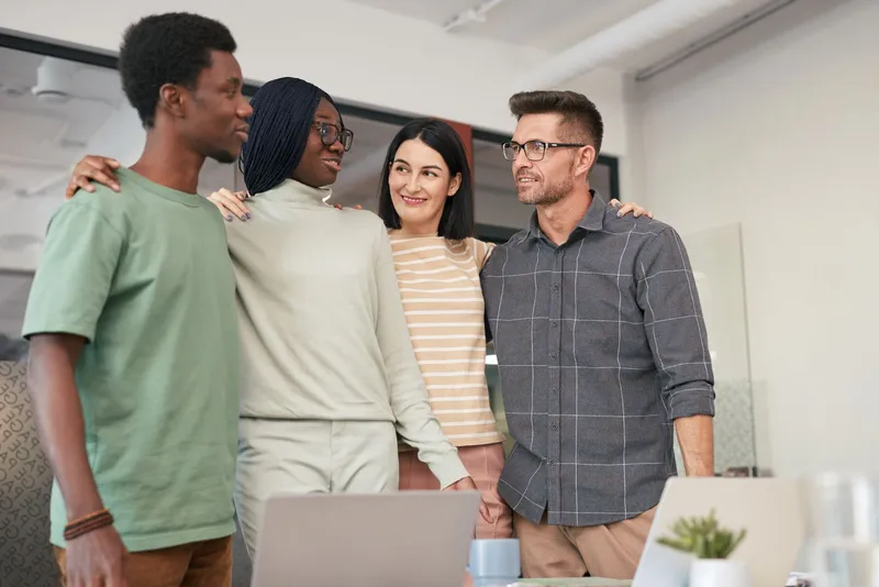 Des membres d'une équipe multidisciplinaire posent ensemble dans un bureau moderne